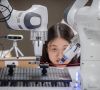 Wissenschaftlerin Keija Chen beobachtet, wie ihr Roboter Kabel in die richtige Position bringt.