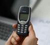 Nokia 3310 in einer Hand vor einem Laptop